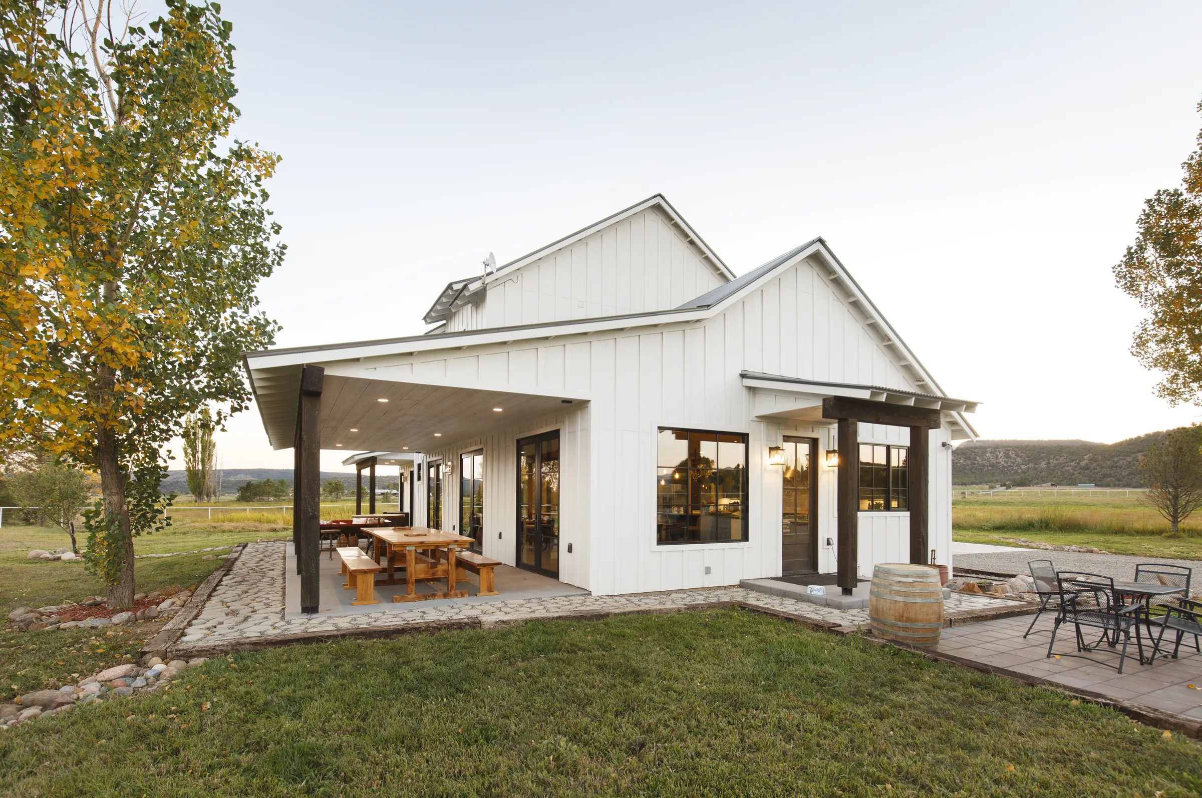 Covered patio and full exterior at dusk, Bright and Airy Farmhouse, Refined Designs by Natalie