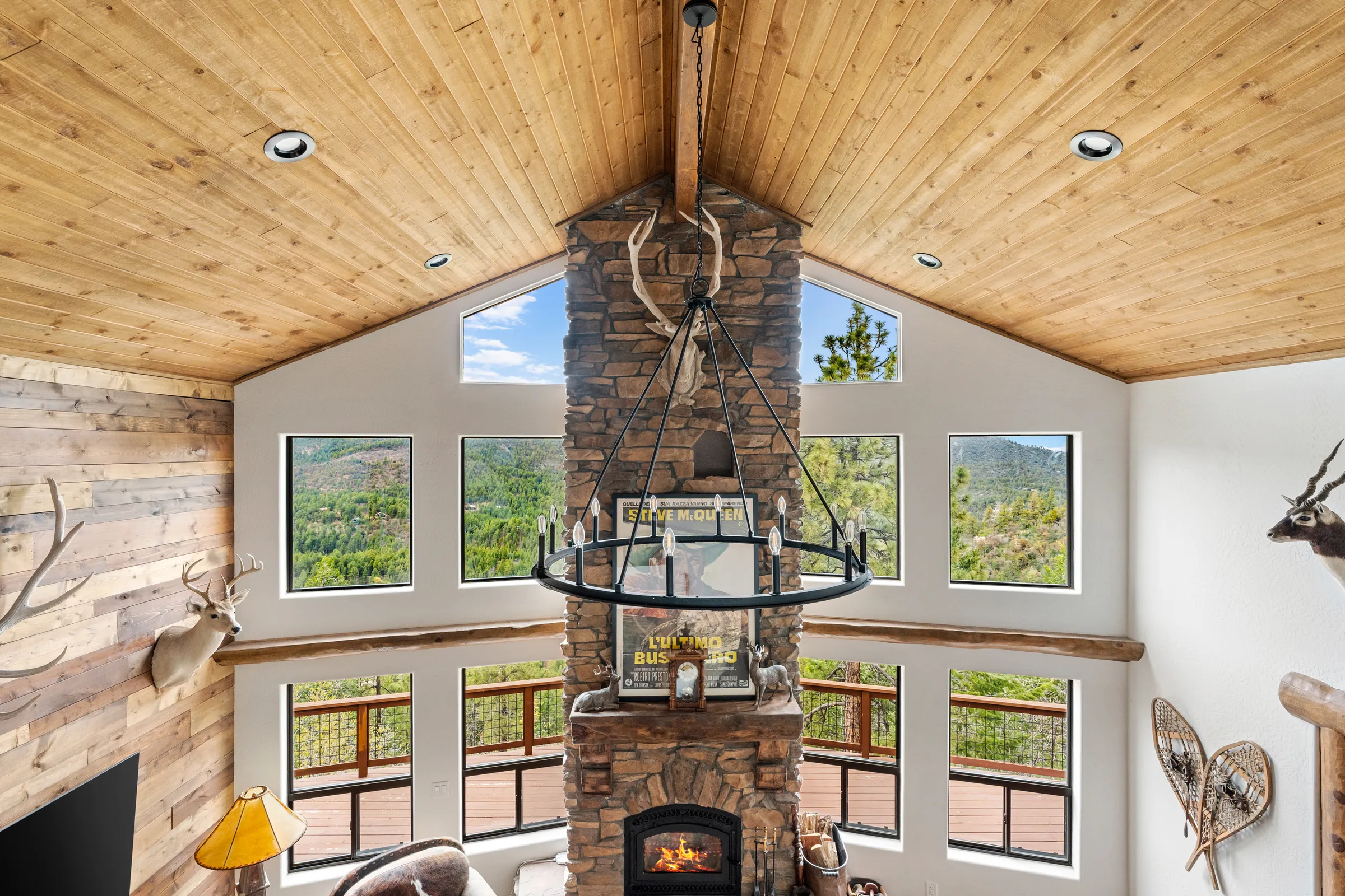 Great room with stone chimney and a wall of windows, seen from the loft, Daybreak at Ponderosa, Refined Designs by Natalie