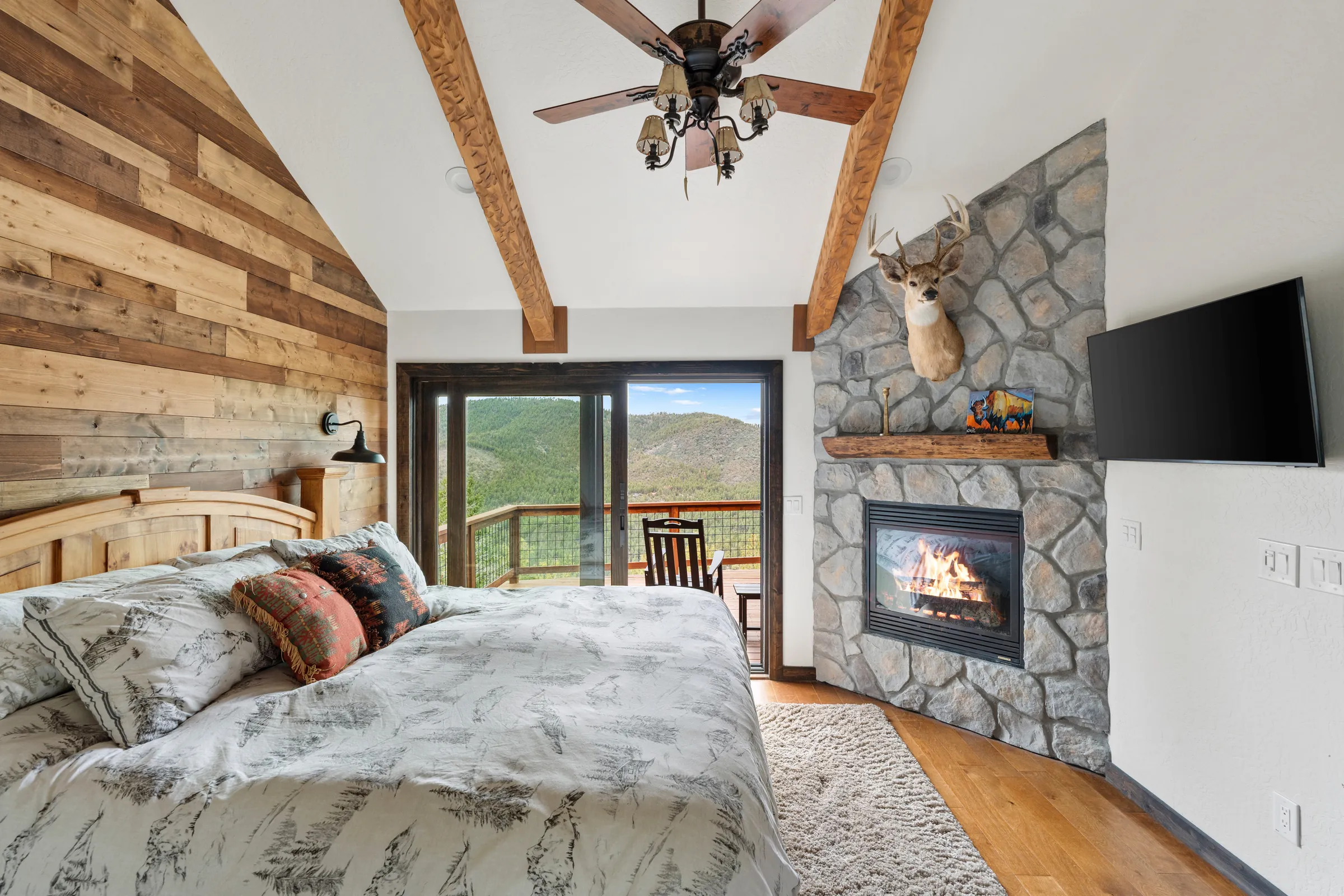 Primary bedroom with stone fireplace and mountain view, Daybreak at Ponderosa, Refined Designs by Natalie